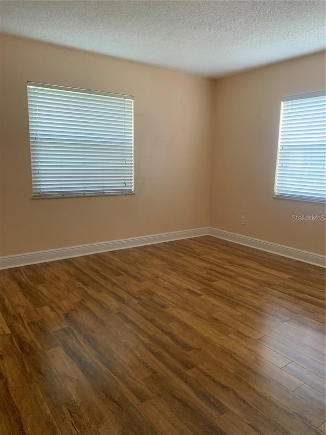 empty room featuring dark hardwood / wood-style flooring and a textured ceiling