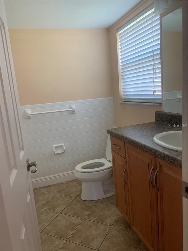 bathroom with tile patterned floors, vanity, toilet, and tile walls