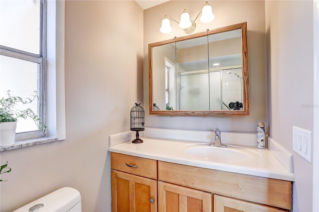 bathroom with a shower with door, vanity, and toilet