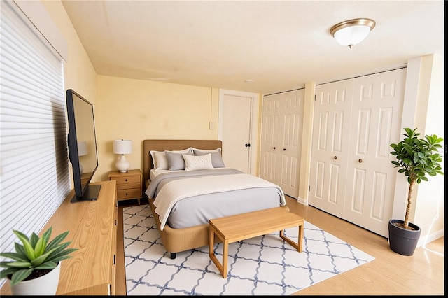 bedroom featuring two closets and light hardwood / wood-style flooring