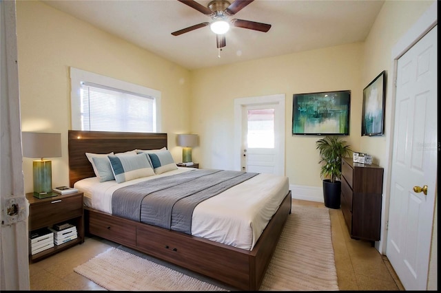 bedroom featuring ceiling fan, ensuite bath, and multiple windows