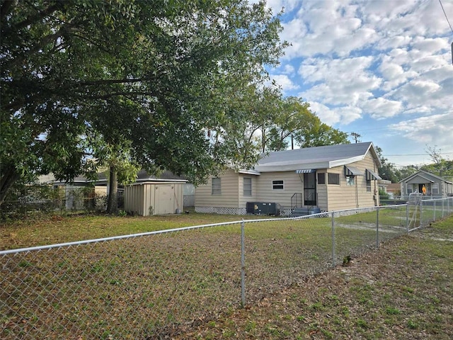 back of house featuring a lawn and a storage unit