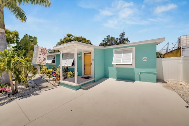 view of front of property with a patio, fence, and stucco siding