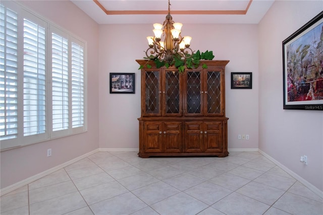 unfurnished dining area with light tile patterned floors, baseboards, and a notable chandelier