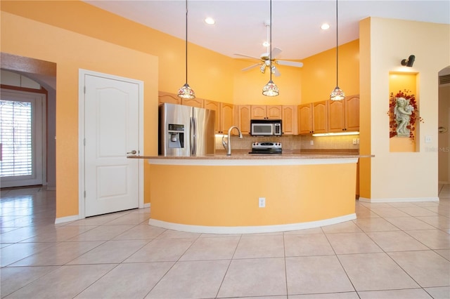 kitchen featuring tasteful backsplash, a center island with sink, a ceiling fan, a high ceiling, and stainless steel appliances