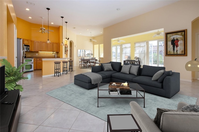 living room with a ceiling fan, arched walkways, recessed lighting, and light tile patterned floors