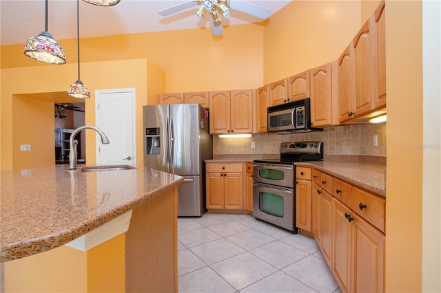 kitchen featuring tasteful backsplash, stainless steel appliances, a sink, and light brown cabinetry