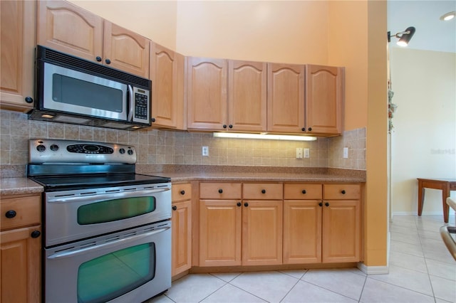 kitchen with light tile patterned floors, light brown cabinets, stainless steel appliances, and decorative backsplash