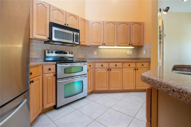 kitchen featuring appliances with stainless steel finishes, tasteful backsplash, light brown cabinets, and light tile patterned floors