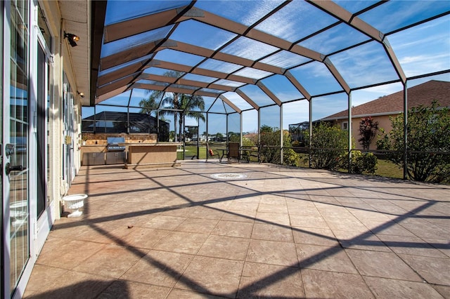 view of patio with glass enclosure, an outdoor kitchen, and a carport