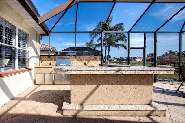 view of patio featuring glass enclosure and area for grilling