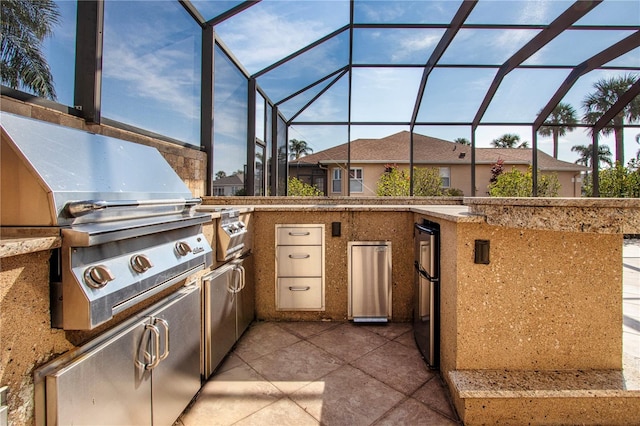 view of patio / terrace featuring a lanai, grilling area, and an outdoor kitchen