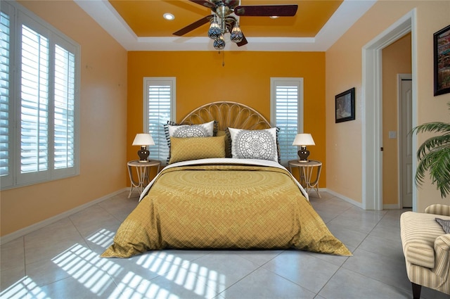 tiled bedroom featuring a ceiling fan, a raised ceiling, and baseboards