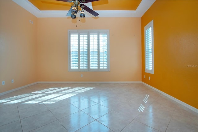 spare room with a tray ceiling, a wealth of natural light, and light tile patterned flooring