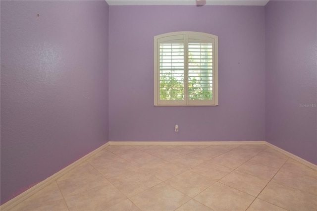 empty room with baseboards and light tile patterned flooring