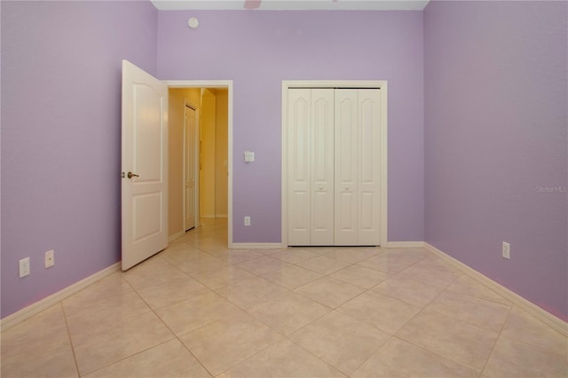 unfurnished bedroom with light tile patterned floors, baseboards, and a closet