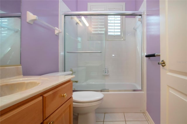 bathroom featuring toilet, vanity, combined bath / shower with glass door, and tile patterned floors