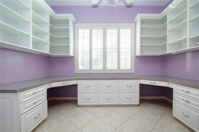 unfurnished office featuring light tile patterned floors, ceiling fan, and built in study area