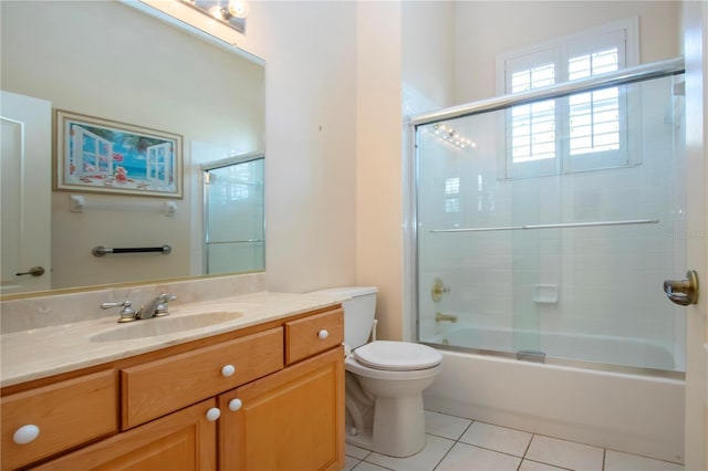 bathroom with toilet, shower / bath combination with glass door, tile patterned flooring, and vanity