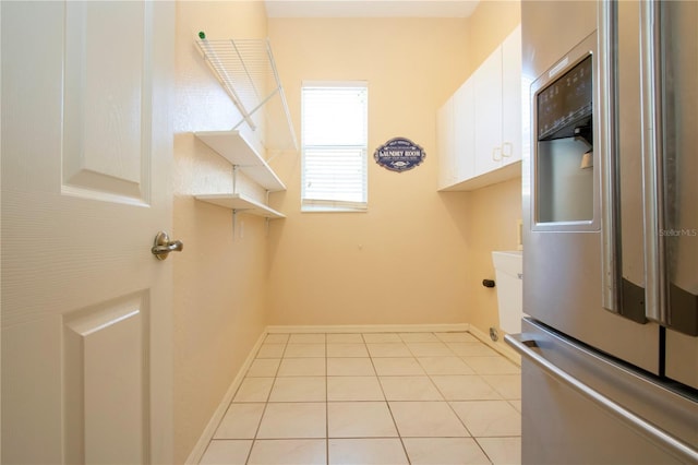 laundry room with cabinet space, baseboards, and light tile patterned floors