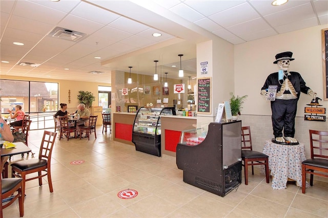 interior space featuring a paneled ceiling, a wainscoted wall, visible vents, and light tile patterned floors