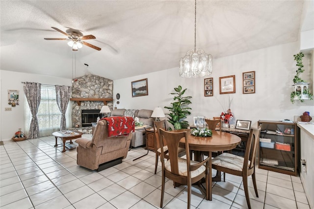 dining room featuring light tile patterned floors, a fireplace, a textured ceiling, ceiling fan with notable chandelier, and vaulted ceiling