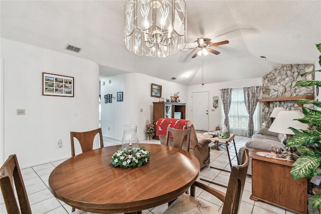 tiled dining room with lofted ceiling, ceiling fan with notable chandelier, and a textured ceiling