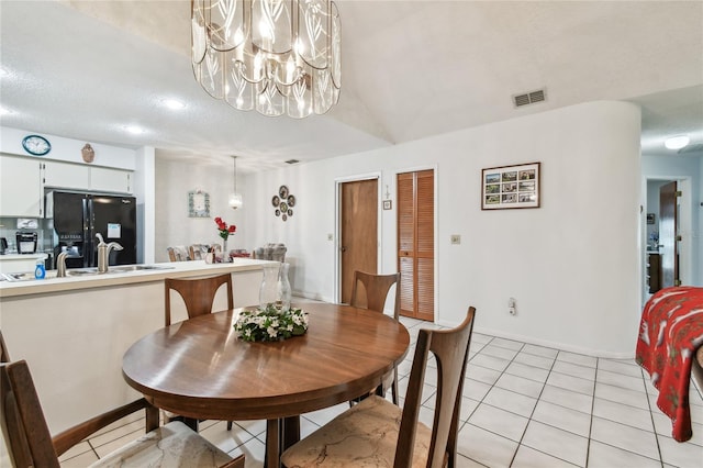 tiled dining space with an inviting chandelier, sink, and a textured ceiling