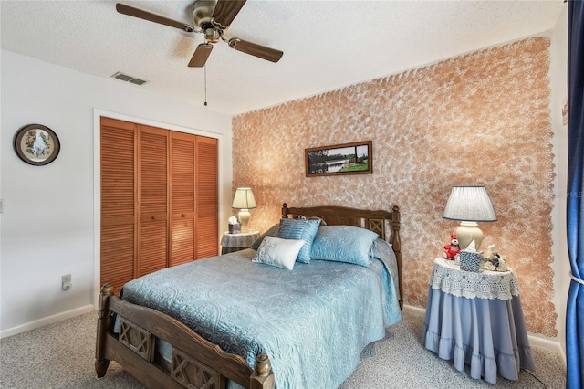 bedroom featuring ceiling fan, light colored carpet, a textured ceiling, and a closet