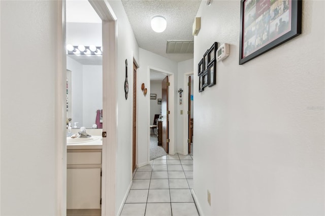 hallway featuring light tile patterned floors and a textured ceiling