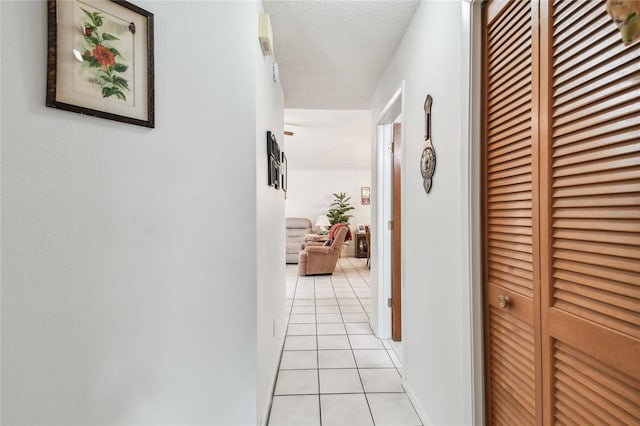 corridor featuring light tile patterned flooring and a textured ceiling