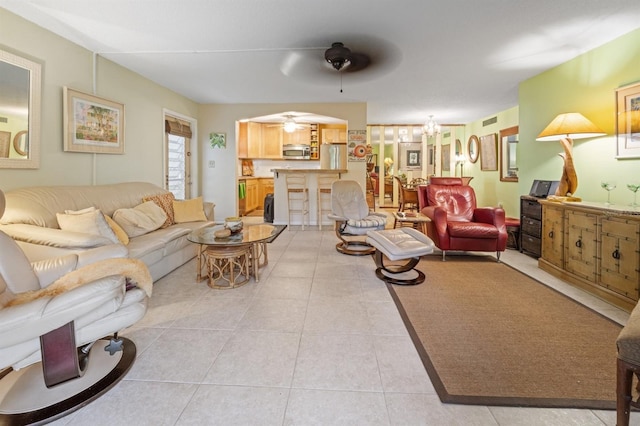 tiled living room featuring ceiling fan with notable chandelier