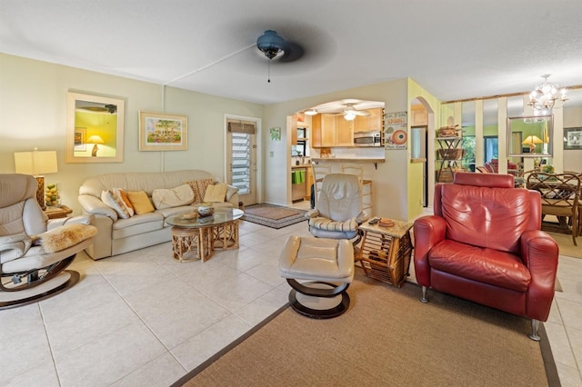 tiled living room with ceiling fan with notable chandelier