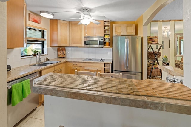 kitchen featuring sink, light tile patterned floors, appliances with stainless steel finishes, decorative backsplash, and light brown cabinets