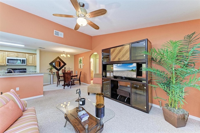 carpeted living room featuring lofted ceiling, sink, and ceiling fan with notable chandelier