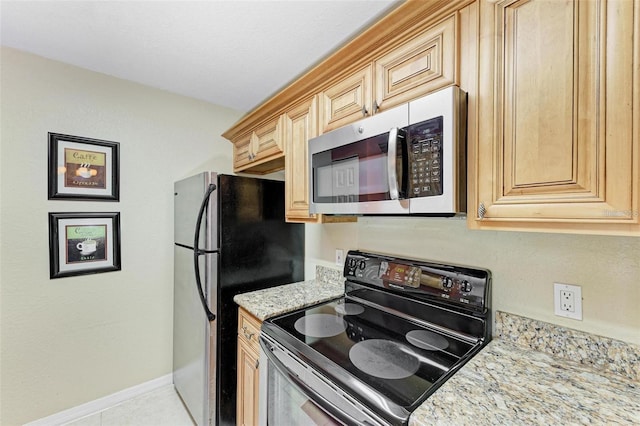 kitchen with light stone counters, light brown cabinetry, light tile patterned floors, and electric range