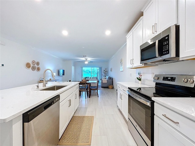 kitchen with sink, white cabinetry, crown molding, an island with sink, and stainless steel appliances