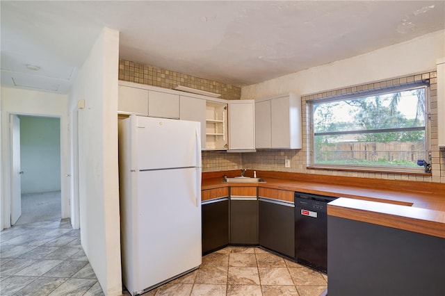 kitchen with white cabinetry, black dishwasher, sink, decorative backsplash, and white refrigerator