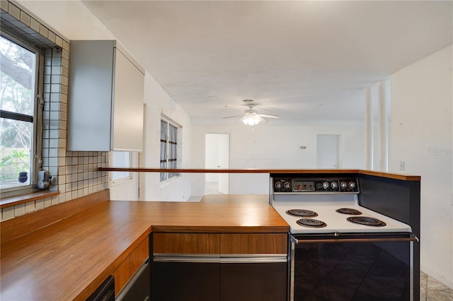 kitchen featuring white electric range, wooden counters, decorative backsplash, ceiling fan, and kitchen peninsula