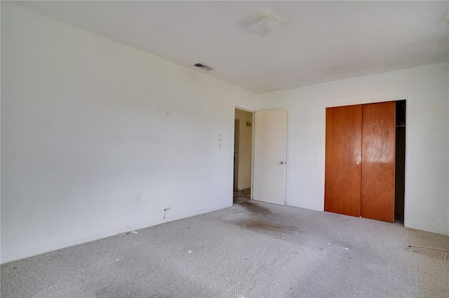 unfurnished bedroom featuring light carpet and a closet