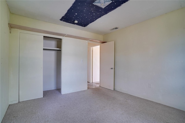 unfurnished bedroom featuring light colored carpet and a closet