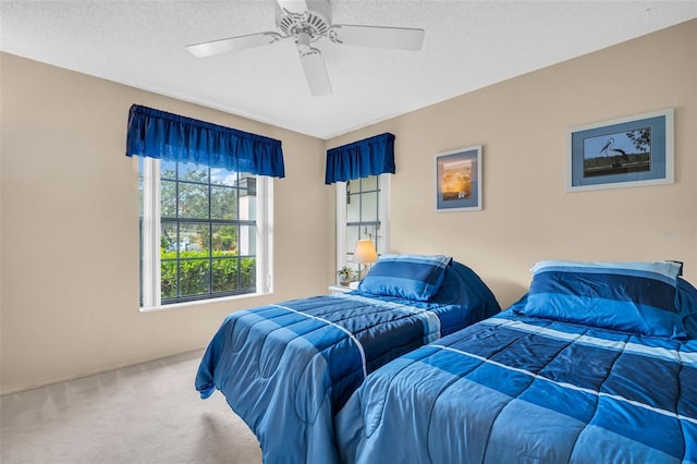 bedroom with ceiling fan, carpet floors, and a textured ceiling