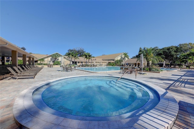 view of pool with a hot tub and a patio