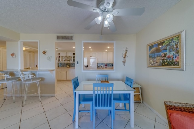 tiled dining area with ceiling fan and a textured ceiling