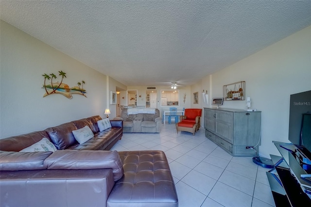 living room featuring ceiling fan, a textured ceiling, and light tile patterned floors