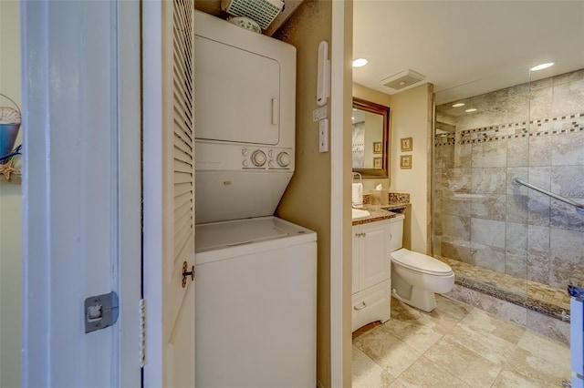 bathroom with stacked washing maching and dryer, tiled shower, vanity, and toilet