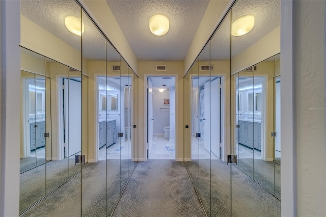 hall with carpet floors and a textured ceiling