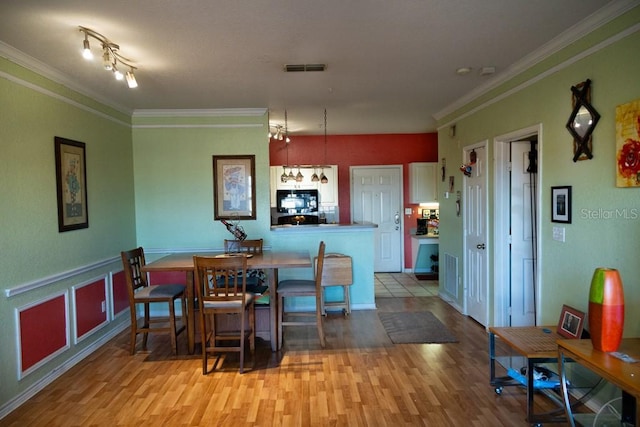 dining space featuring ornamental molding and light hardwood / wood-style floors