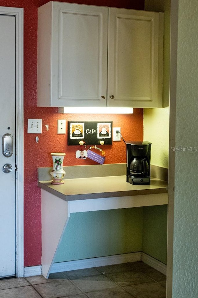 kitchen featuring built in desk, white cabinets, and light tile patterned flooring