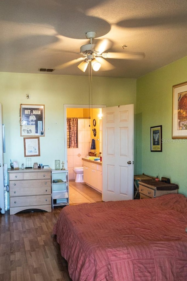 bedroom featuring hardwood / wood-style flooring, ceiling fan, a textured ceiling, and ensuite bath